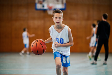 A junior basketball player in action dribbling a ball towards camera.