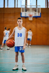 Portrait of a boy with a basketball on court during the training.