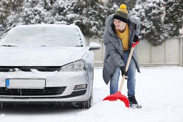 Man removing snow with shovel near car outdoors