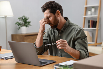 Naklejka premium Tired man suffering from headache at workplace