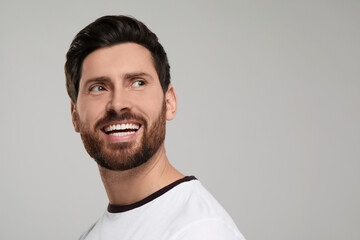 Portrait of smiling man with healthy clean teeth on light grey background. Space for text