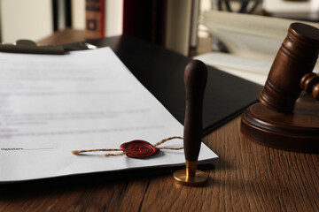 Document, stamp and gavel on wooden table, closeup. Notary contract
