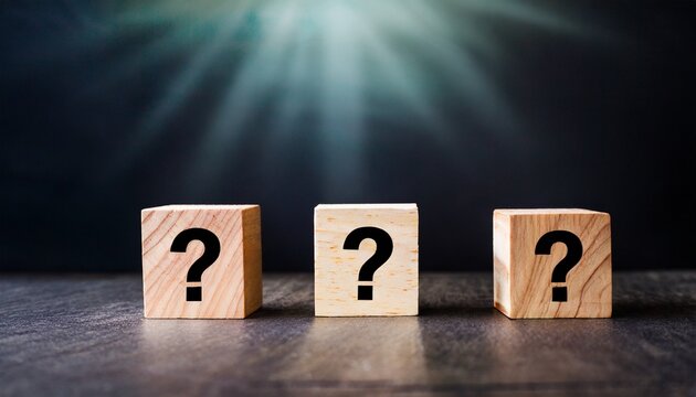 three wooden blocks with question marks in the foreground in a conceptual image on dark