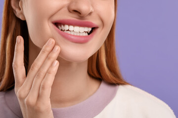 Woman with clean teeth smiling on violet background, closeup. Space for text