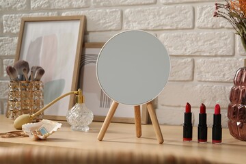 Mirror, makeup products, perfume and jewelry on wooden dressing table
