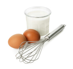 Metal whisk, raw eggs and glass of milk isolated on white