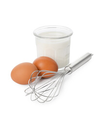 Metal whisk, raw eggs and glass of milk isolated on white