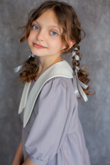 Beautiful teenage girl with big blue eyes pigtails and a gray school dress with a white collar