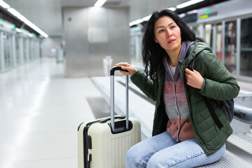 Asian woman sitting in subway station and waiting for train arrival