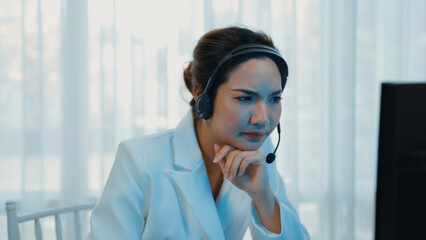 Businesswoman wearing headset working in office to support remote customer or colleague. Frustrated...