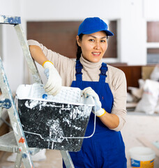 Asian woman repair worker standing in apartment and looking at camera.