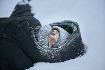 Person Laying in Snow With Hood On - obrazy, fototapety, plakaty