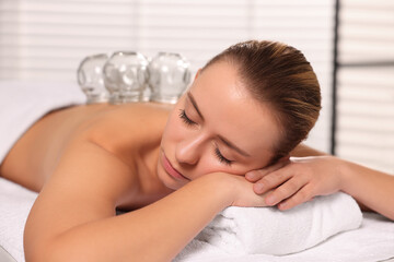 Cupping therapy. Woman with glass cups on massage couch in spa salon