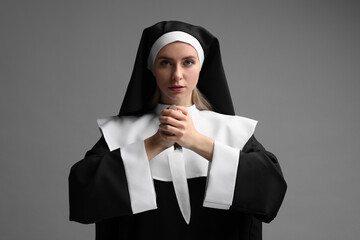 Woman in nun habit holding knife on grey background