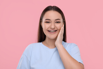 Fototapeta premium Smiling woman with dental braces on pink background