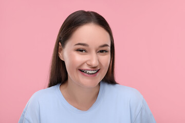 Fototapeta premium Smiling woman with dental braces on pink background