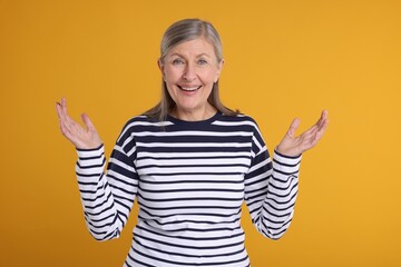 Portrait of happy surprised senior woman on yellow background