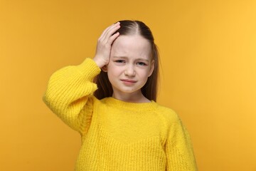 Little girl suffering from headache on yellow background