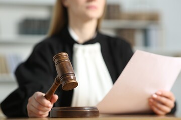 Judge striking mallet at table indoors, closeup