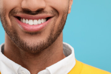 Fototapeta premium Smiling man with healthy clean teeth on light blue background, closeup