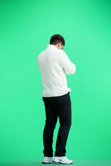 Fototapeta premium A man, full-length, on a green background, looks at his watch