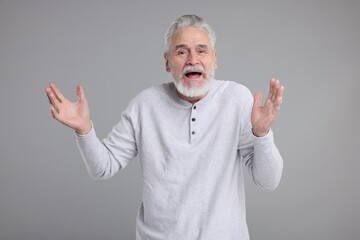 Portrait of surprised senior man on grey background