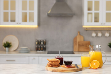 Fototapeta na wymiar Breakfast served in kitchen. Crunchy toasts, jam and orange fresh on white table. Space for text