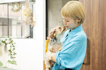 ドッグサロンでヨークシャーテリアを抱くショートヘアの女性