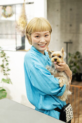 ドッグサロンでヨークシャーテリアを抱くショートヘアの女性