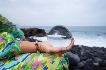 woman meditating on beach shore and holding crystal ball