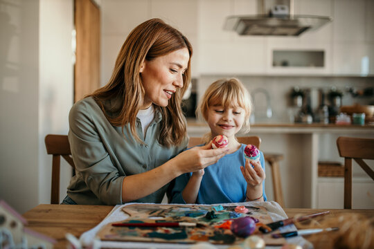 Heartwarming scene of a mother and daughter joyfully decorating Easter eggs together
