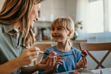Mom and daughter working together to make beautifully decorated Easter eggs