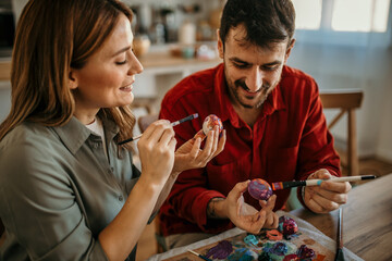 Joyful couple immersed in Easter spirit, delicately decorating vibrant eggs with love