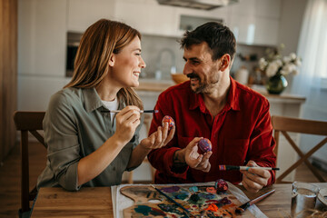 Cute couple engaged in a festive Easter egg decorating session, sharing smiles and laughter