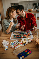Affectionate couple enjoying quality time, adding intricate details to Easter eggs