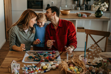 A loving family of three making lasting memories while decorating eggs in the comfort of their...