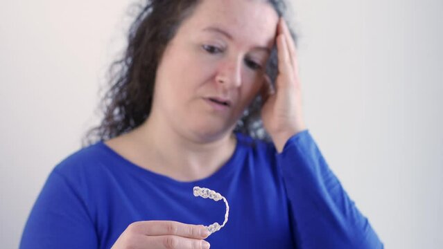Close up of a worried woman hand holding her worn and broken silicone trainer with white background