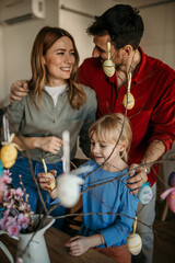 Happy family gathered around the dining table, immersed in painting eggs and beautifying their Easter tree