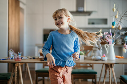 Playful girl dancing and enjoying in the dining room during a creative Easter painting
