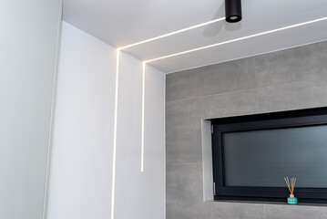 LED light strips mounted in the wall and ceiling in a modern bathroom, window visible.