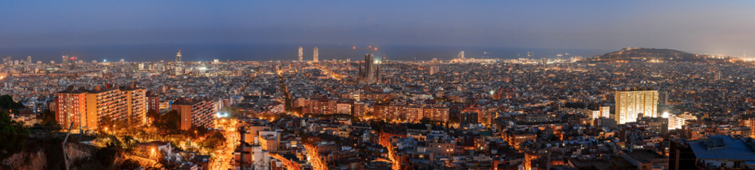 Fototapeta na wymiar Panoramic evening view of Barcelona, Spain, showcasing its urban glow with lit streets and buildings against a dusk sky, hinting at its coastal setting and vibrant nightlife.