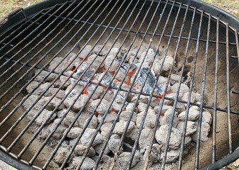 Old, kettle grill filled with red hot charcoal ready to begin cooking