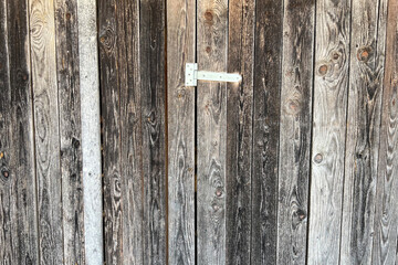 Background: old silver gray wooden wall with a door held by a hinge