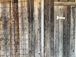 Background: old silver gray wooden wall with a door held by a metal hinge