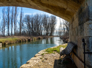 Nice view of the Canal de Castilla from under a bridge with a bench to rest. Castromocho, Palencia, Spain.