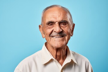 Portrait of a smiling senior man looking at camera on blue background