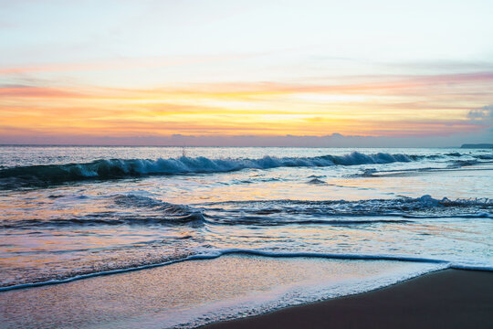 The sun gracefully dips below the horizon, casting warm hues across the tranquil sands during a sunset