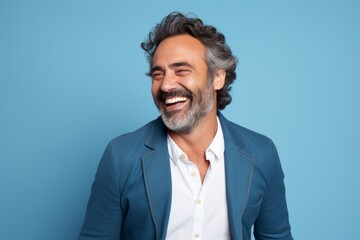 Handsome middle aged man laughing and looking at camera isolated over blue background