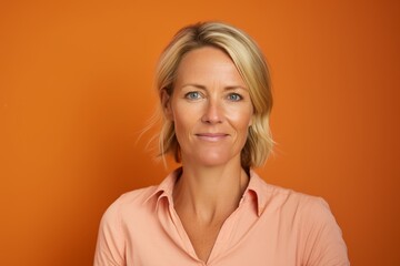 Portrait of a beautiful middle aged woman with blond hair on orange background