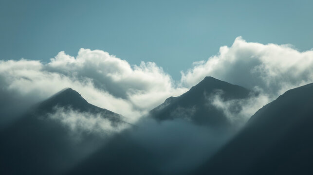 The subtle movement of clouds drifting over the shadowed peaks.